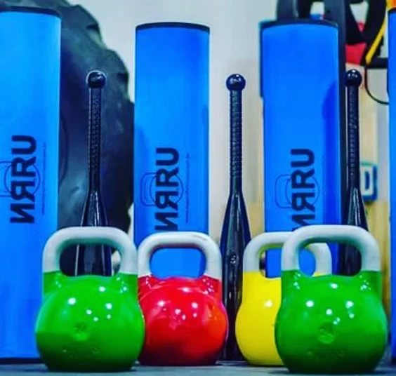 Clubbells NRRU azuis ao lado de kettlebells coloridos